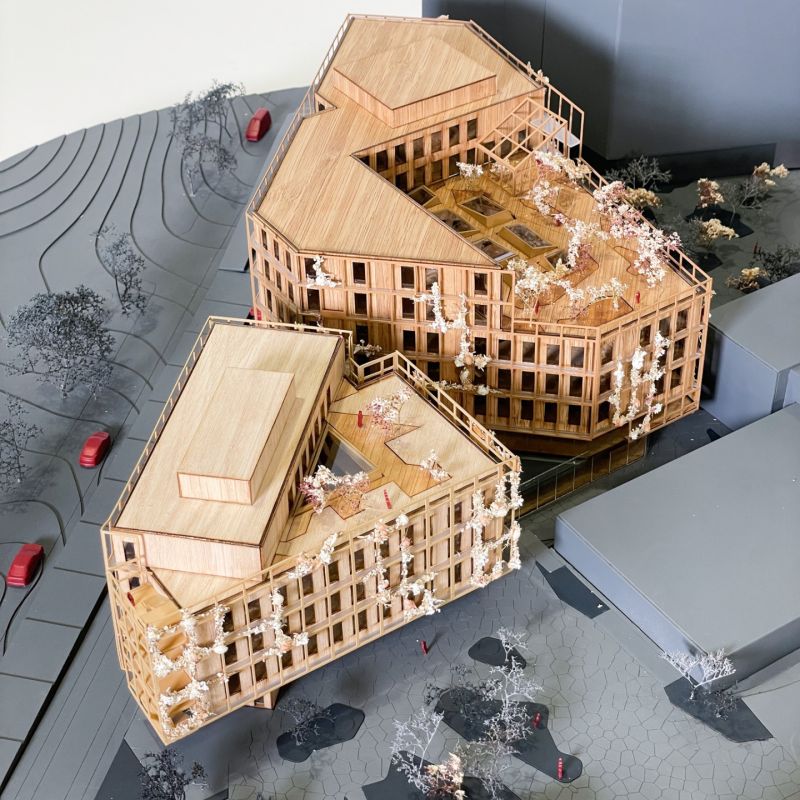 Fysisk modell av campus, med de to nye byggene i tre mot det grå omlandet.