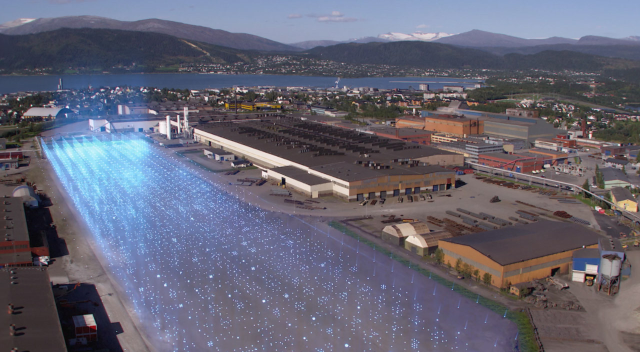 GIGA ARCTIC sett fra lufta: batterifabrikken lagt inn i industriområdet i Mo i Rana, med fjorden og fjellene bak.